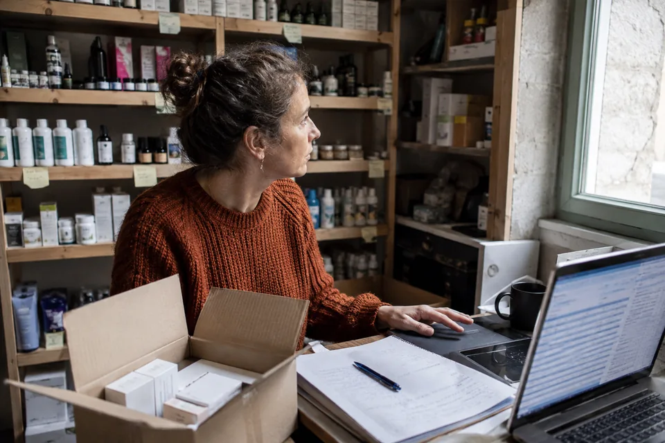 A shopkeeper prepares a reorder on her computer in the stockroom.