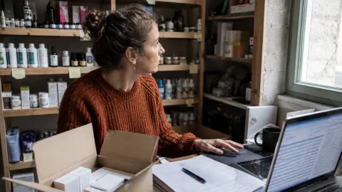 Une commerçante prépare un réassort sur ordinateur dans sa réserve.